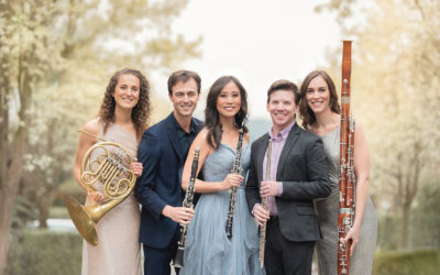Five members of the music ensemble WindSync standing outside holding their instruments