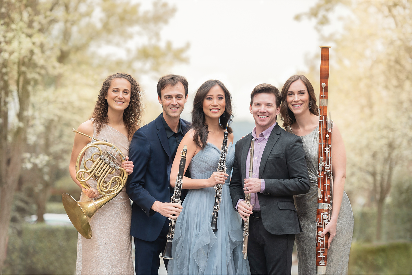Five members of the music ensemble WindSync standing outside holding their instruments